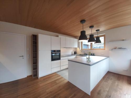 a kitchen with white cabinets and a wooden ceiling at Auszeit in Buch
