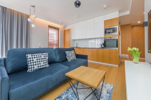 a living room with a blue couch and a kitchen at Sunny Wood - Bursztynowa in Gdańsk