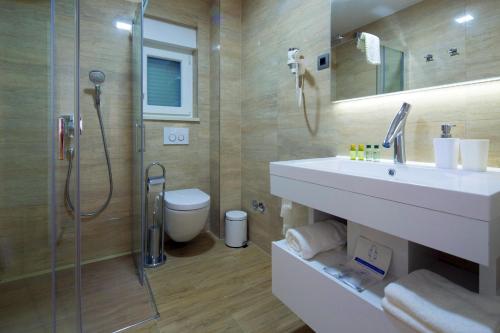 uma casa de banho com um lavatório, um chuveiro e um WC. em Apartments The Seasons Residence em Omiš
