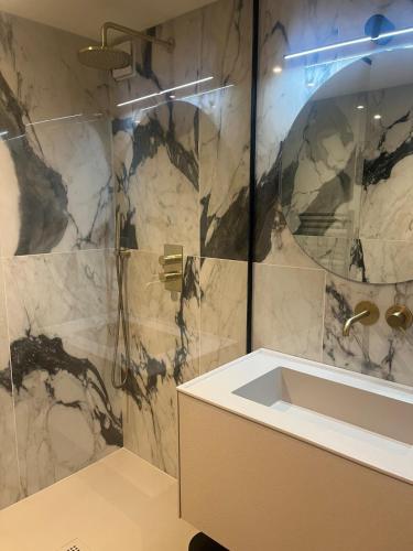 a bathroom with a shower with a sink and a mirror at Maison en bois avec piscine chauffée et vue panoramique in Argonay
