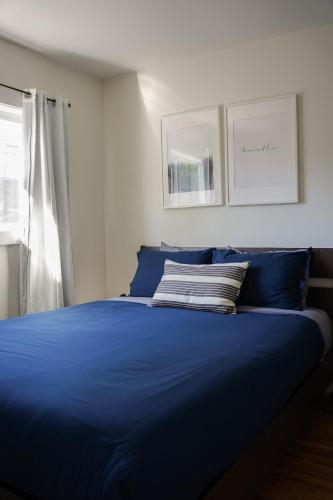 a blue bed in a room with a window at Coastal Suite - Harbourview in Ucluelet in Ucluelet