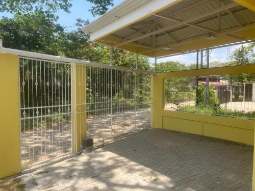 a screened in porch with yellow walls and windows at Peaceful and beautiful Casa Almita Bonita in Sámara