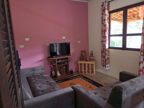 a living room with two couches and a tv at Casinha nas montanhas in Gonçalves
