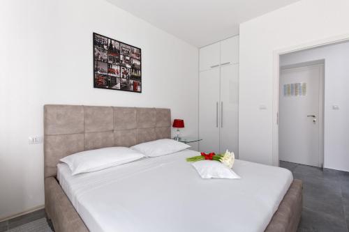 a bedroom with a large white bed with a flower on it at Apartments Kala & Kaleta in Split