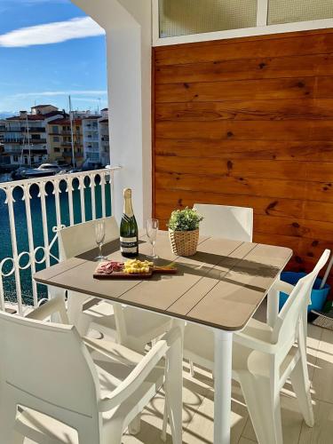 a table with a bottle of wine and chairs on a balcony at Marina View Empuriabrava - Appartement sud-ouest au canal avec terrasse in Empuriabrava