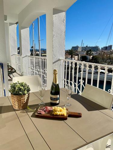 a bottle of wine and glasses on a table on a balcony at Marina View Empuriabrava - Appartement sud-ouest au canal avec terrasse in Empuriabrava
