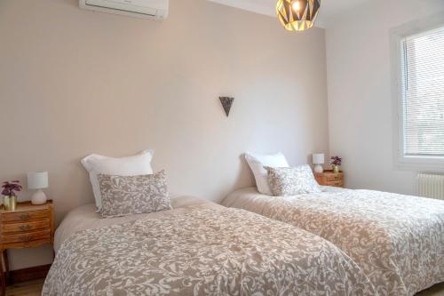 une chambre avec deux lits et un lustre dans l'établissement Standing de 88 m2, grand jardin, wifi, clim, Netflix, La Suzanna, à Hyères