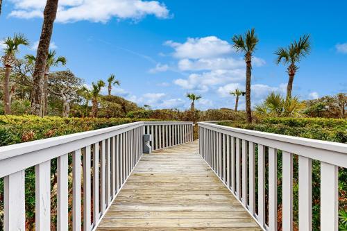 a wooden boardwalk leading to the beach with palm trees at Shipwatch 2373 in Kiawah Island