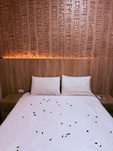 a bedroom with a white bed with a wooden wall at Locanda pyramids view in Cairo