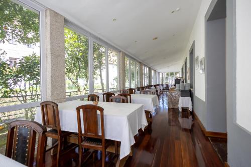 uma sala de jantar com mesas e cadeiras brancas e janelas em Hotel Universal no Gerês