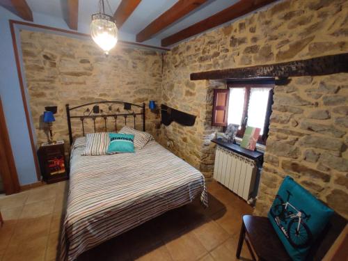 a bedroom with a bed and a stone wall at El Hogar del Ciclista in Espinosa de los Monteros