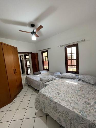 a bedroom with two beds and a ceiling fan at Casa a 2 minutos do santuário Nossa Senhora aparecida in Aparecida