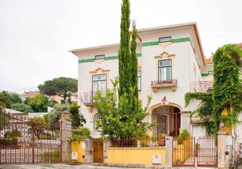 a large white house with a fence and trees at Adore Portugal Coimbra Guest House in Coimbra