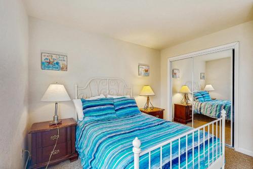 una camera da letto con un letto con un piumone blu e uno specchio di Seaside Serenity a Seaside