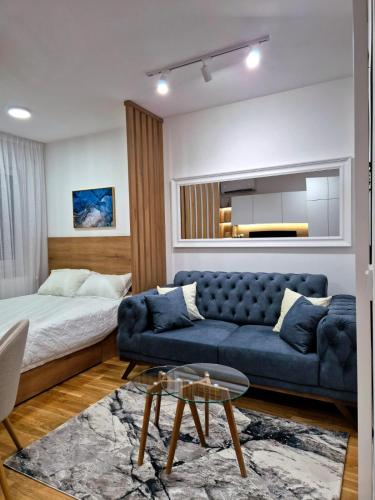 a living room with a blue couch and a bed at Sokolis Apartman in Kragujevac