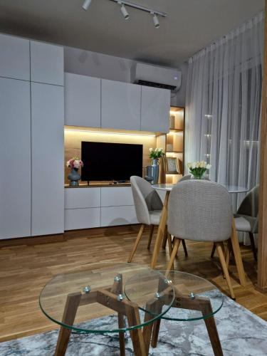 a living room with a table and chairs and a television at Sokolis Apartman in Kragujevac