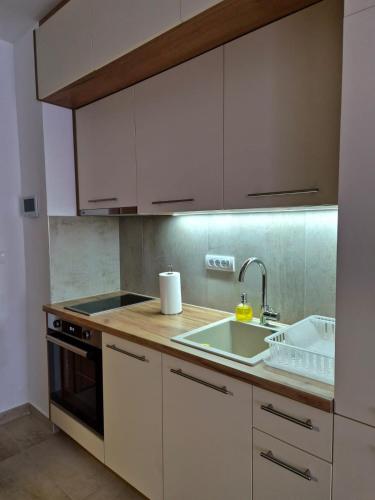 a kitchen with white cabinets and a sink at Sokolis Apartman in Kragujevac