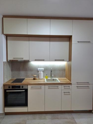 a kitchen with white cabinets and a sink at Sokolis Apartman in Kragujevac