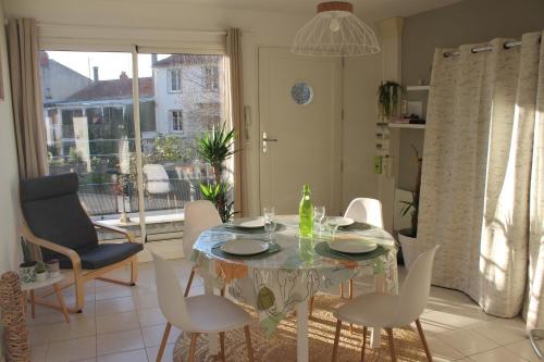 a dining room with a table and white chairs at Appartement cosy terrasse parking privé 2 vélos in La Rochelle