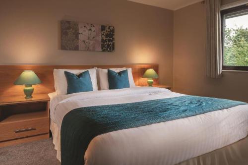 a bedroom with a large bed with blue pillows at Rutland Hall Hotel & Spa in Burley