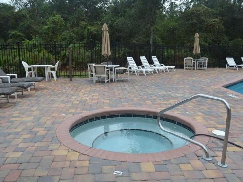 a hot tub in a patio with chairs and tables at 2492-3-SW-Spacious Condo in Kissimmee