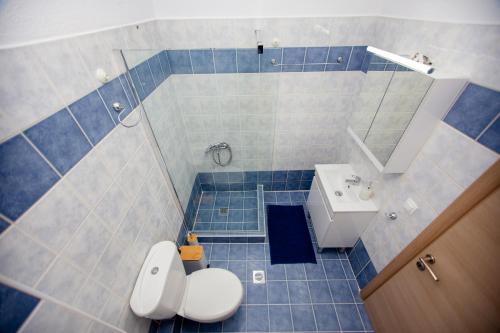 a blue tiled bathroom with a toilet and a sink at Angelica's Apartment in Asprovalta