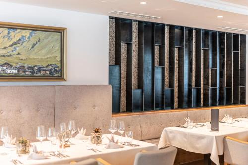 a restaurant with white tables and chairs and a painting at Premium Activehotel Bergkönig in Neustift im Stubaital