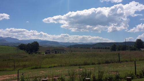 a house in the middle of a field with a fence at J&B Lodge in Underberg