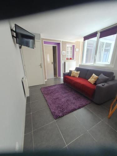 Il comprend un salon doté d'un canapé rouge et d'une télévision à écran plat. dans l'établissement appartement 2 pieces, à Deauville