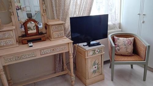 a television on a dresser with a chair and a mirror at Areti's Captain's House with Private Terrace in Galaxidhion