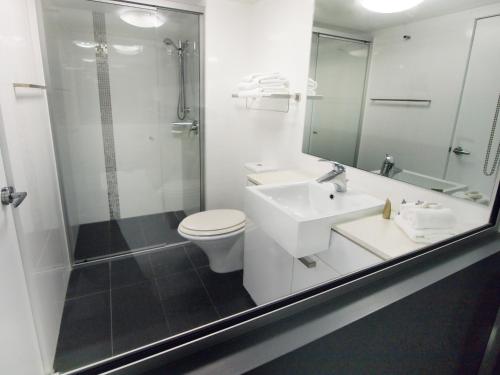 a bathroom with a sink and a toilet and a shower at Oaks Townsville Metropole Hotel in Townsville