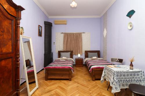a room with three beds and a table and a mirror at Leon Rooms in Tbilisi City