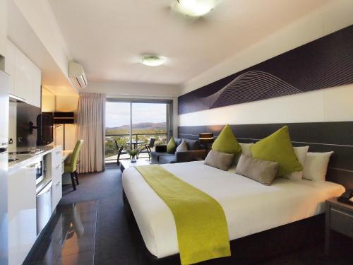 a hotel room with a large bed and a kitchen at Oaks Townsville Metropole Hotel in Townsville
