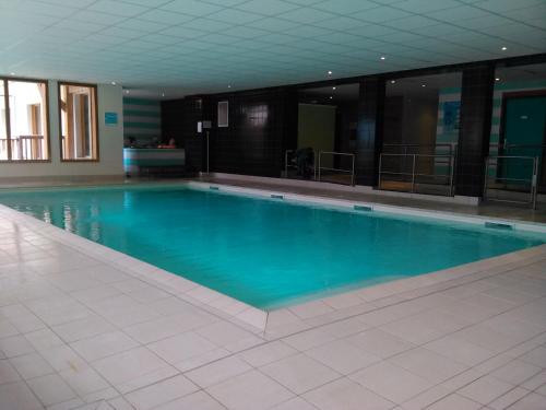une grande piscine avec de l'eau bleue dans un immeuble dans l'établissement Les Chalets de Bois Méan-Les Orres 1800-Appt Duplex-6 couchages, aux Orres