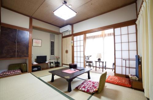 a living room with a table and some chairs at Hinodeya in Ito