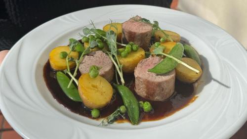 a white plate of food with meat and vegetables at Mleczarnia Hotel Restauracja in Chludowo