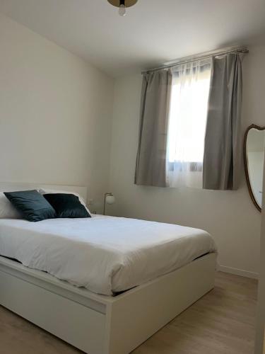 a white bedroom with a bed with a window at AL 31 Bg in Bergamo