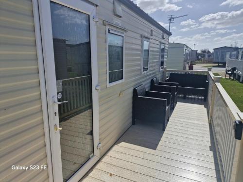 a large deck with benches on the side of a house at 3-Bed Caravan Sleeps 8 Pool & Beach in Chapel Saint Leonards