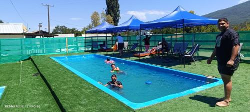 a man standing in a swimming pool with a child in it at Cabañas y piscinas sabor a campo embalse ancoa in Los Rabones