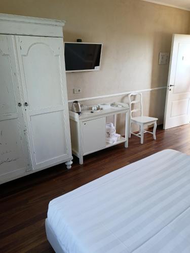 a white bedroom with a bed and a cabinet and a tv at B&B La Quercia in Moncalvo