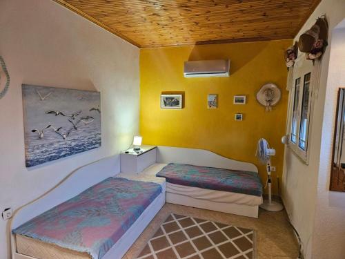 two beds in a room with yellow walls at VITA House in Nea Kalikratia