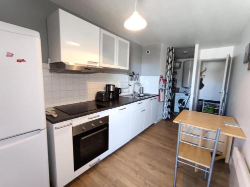- une cuisine avec des appareils blancs et une table en bois dans l'établissement Résidence Les Miandettes - Grand appartement aux pieds des pistes MAE-8444, à Montgenèvre