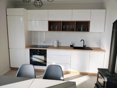 a kitchen with white cabinets and a sink and a stove at Domek letniskowy nad morzem in Osieki Leborskie