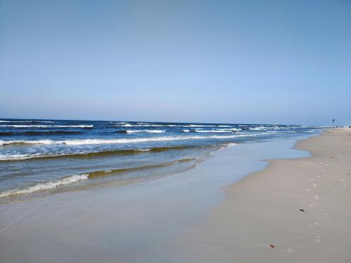 a sandy beach with waves in the ocean at Domek letniskowy nad morzem in Osieki Leborskie