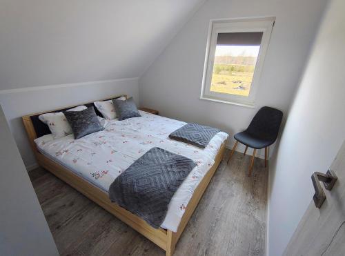 a bedroom with a bed with a window and a chair at Domek letniskowy nad morzem in Osieki Leborskie