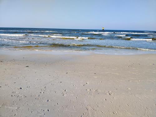 a sandy beach with waves in the ocean at Domek letniskowy nad morzem in Osieki Leborskie