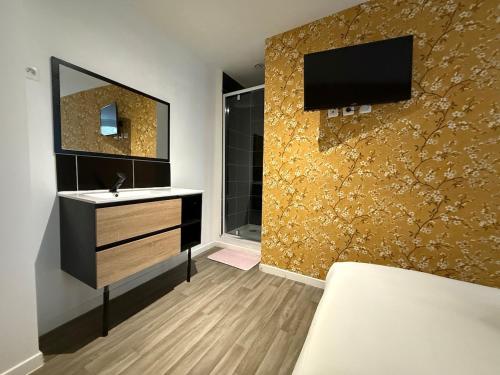 a bathroom with a sink and a tv on a wall at Suite Jaune #4#- Douceur & confort-self check-in in Roubaix