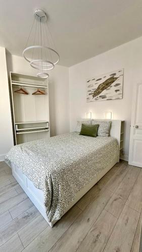 - une chambre blanche avec un lit et un lustre dans l'établissement Maison Cosy à Vichy, à Vichy