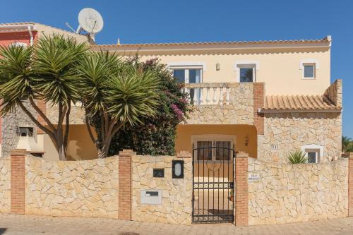 a house behind a stone wall with a gate at Villa Arpeggio - Cozy 3-Bedroom Villa with Private Pool in Montinhos da Luz, Lagos in Mato Porcas