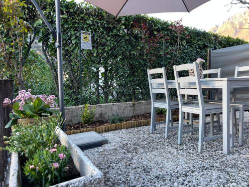 a patio with two chairs and a table with an umbrella at BloomHouse - apartment in Porlezza
